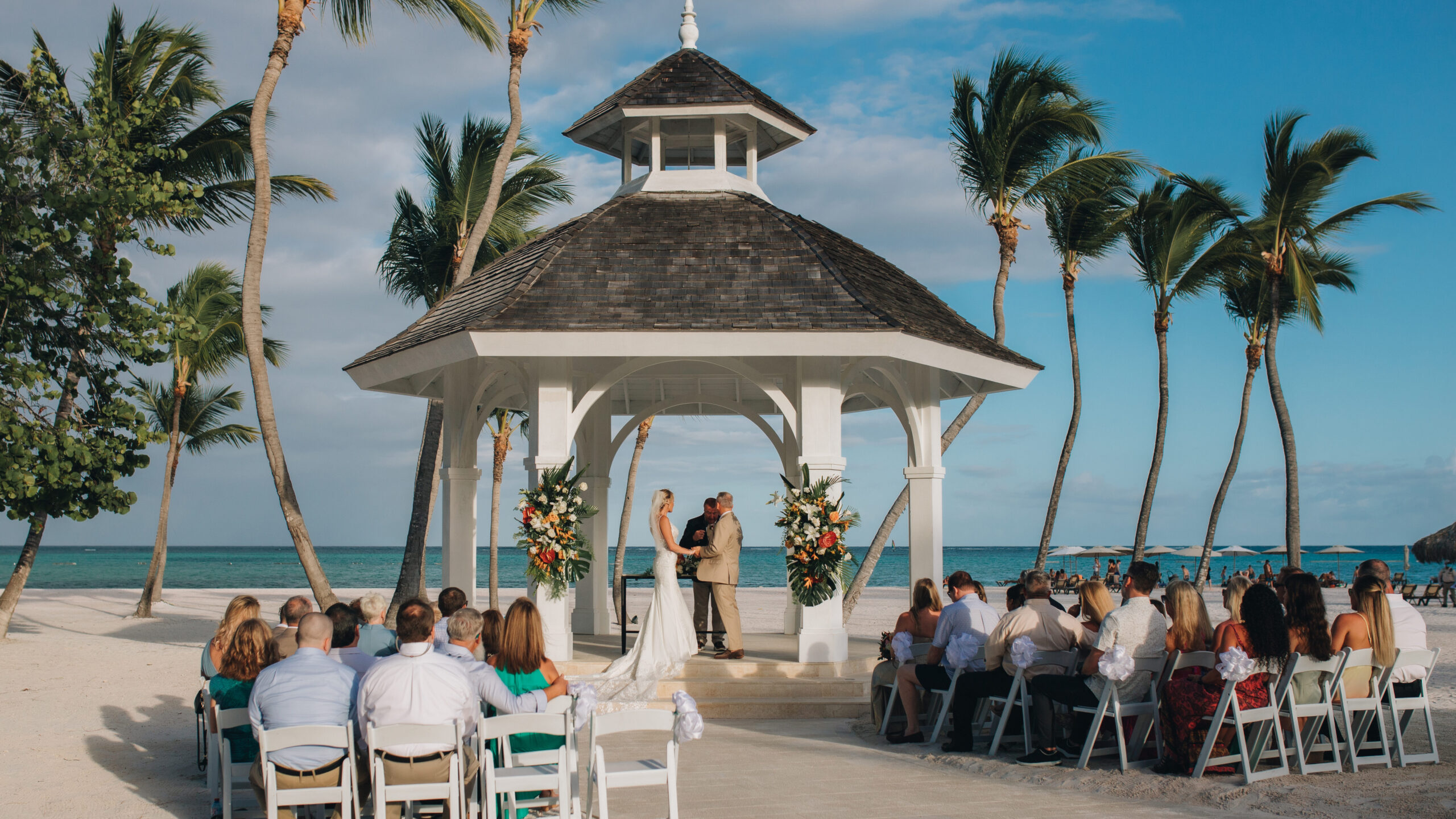 Bride and groom and destination wedding, located on a beautiful beach with wedding guests present.