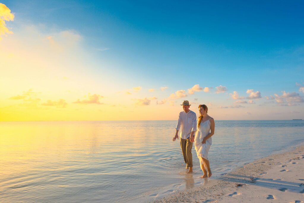 A couple taking a romantic walk on the beach. Many times planning the perfect honeymoon involves a stay at the beach.